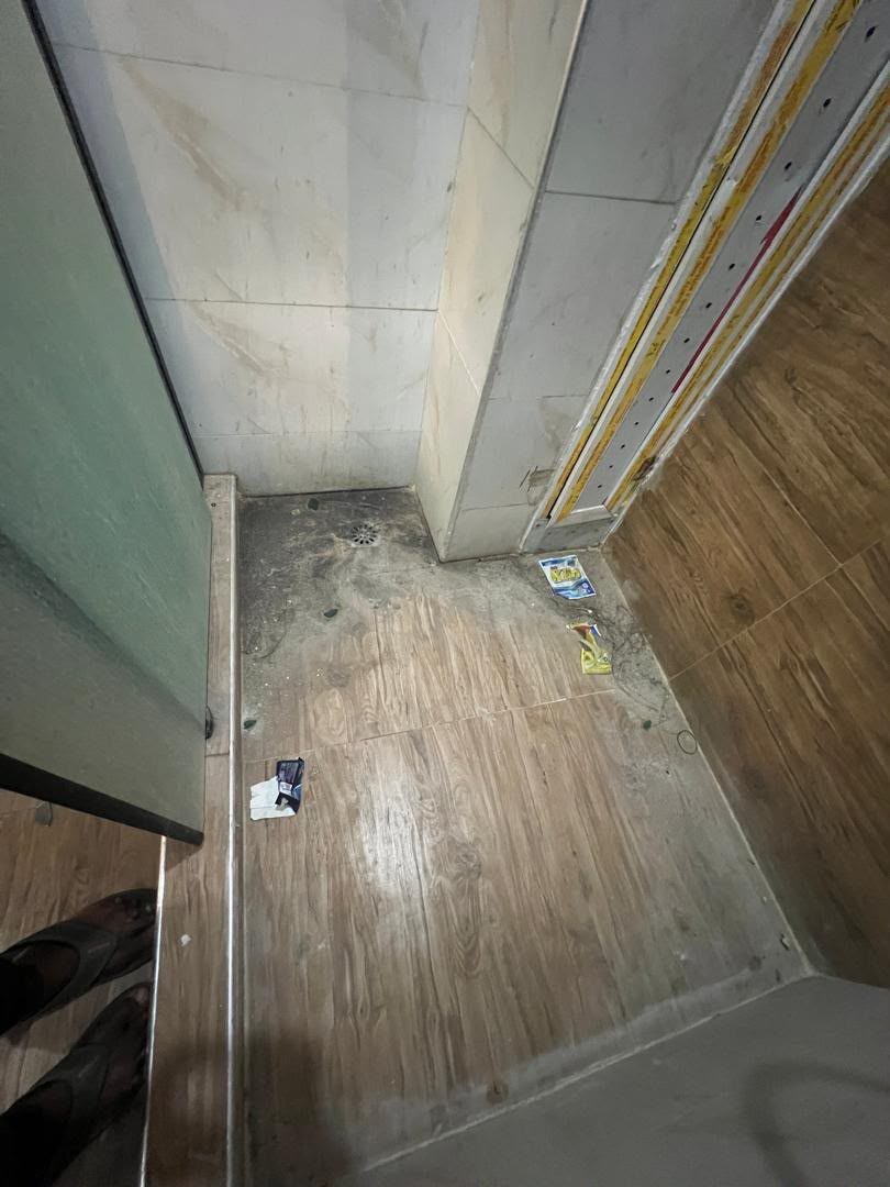 Bathroom floor covered in construction dust and debris