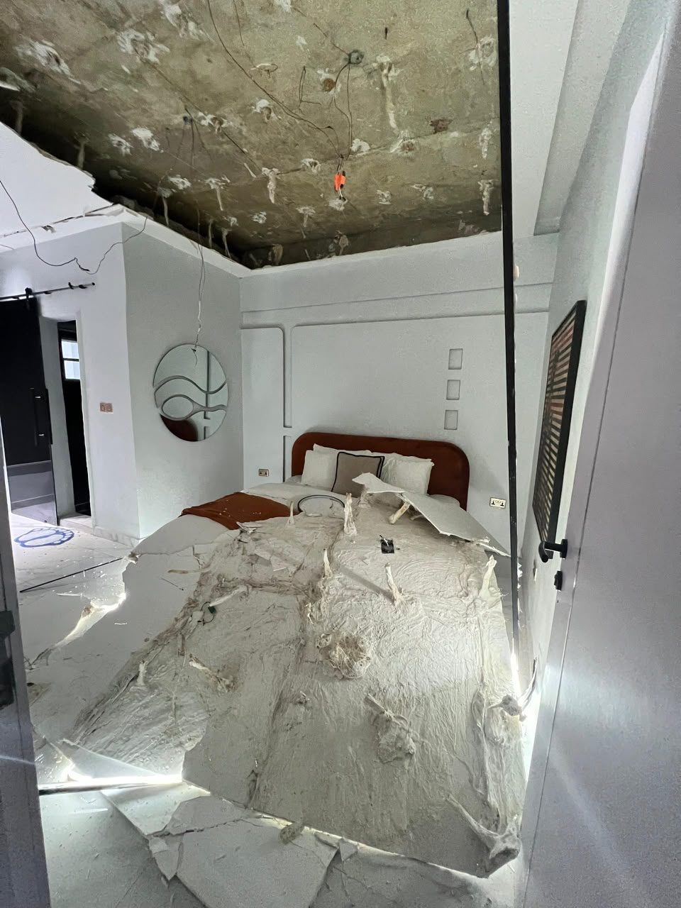 Bedroom with heavy ceiling damage and debris on the bed